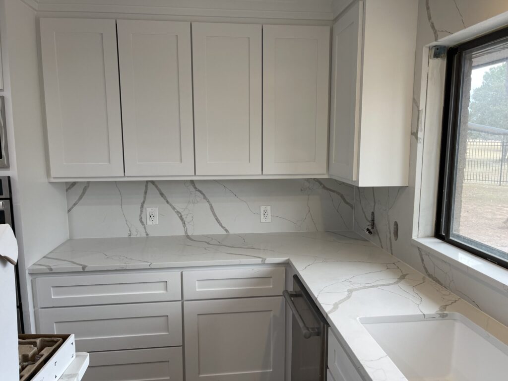 Beautiful granite kitchen countertop with modern white custom cabinets in a spacious kitchen layout